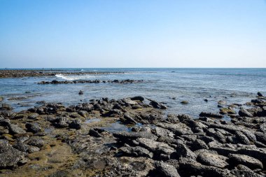 Rocky Coastal Landscape with Clear Blue Sky and Serene Ocean View