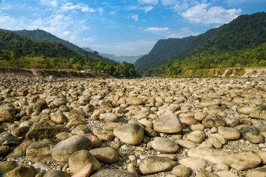 İnsanlar yemyeşil tepeler ve dağ vadileri arasında Kayalık Nehir yatağını keşfediyor.