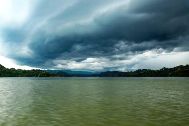 Stormy Lake Landscape Under Heavy Clouds Over Calm Water and Forested Shoreline