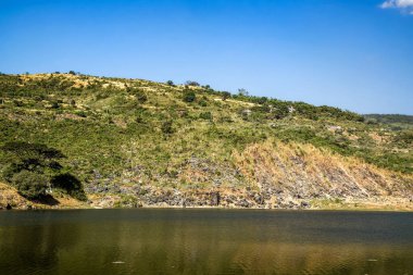 Scenic Lake Surrounded by Hills and Clear Blue Sky