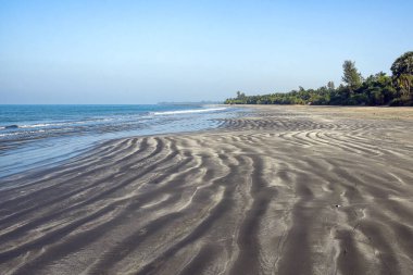 Güzel sahil sahili dalgalanan kum desenleri, turkuaz deniz, berrak gökyüzü ve bereketli tropikal bitki örtüsü, dinlenme ve keşif için ideal huzurlu ve davetkar bir doğal varış yeri yaratıyor..