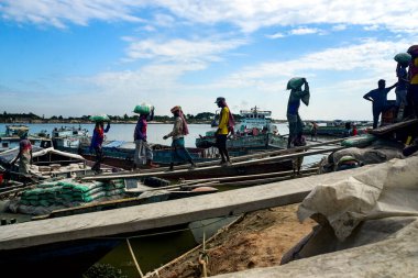 Kereste ve rıhtımlardaki tekneleri taşıyan işçilerle dolu Nehir Kıyısı Sahili