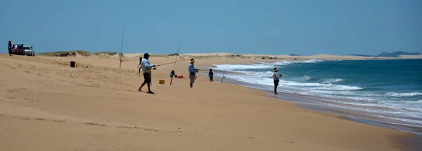 Мужчины рыбачат на песчаном пляже — стоковое фото