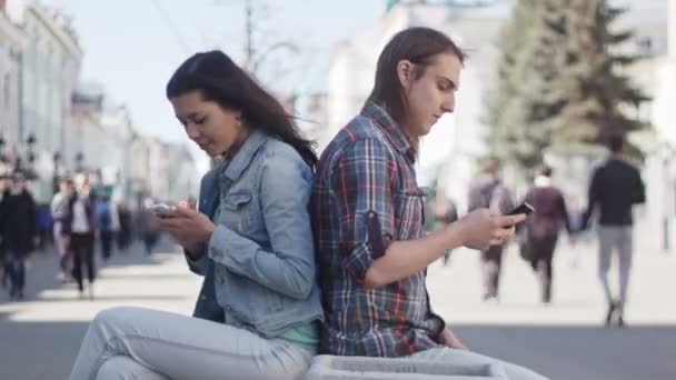 Niedliche Mädchen und Jungen mit langen Haaren verwenden Gadgets auf einer Straße in Dating-Zeitraffer, Russland, Kasan, 27.04.2016 — Stockvideo