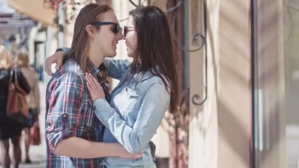 Милая девочка и мальчик с длинными волосами в темных очках целуются на улице — стоковое видео