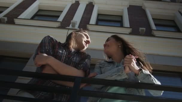 Ragazza carina e ragazzo con i capelli lunghi si trova vicino edificio — Video Stock