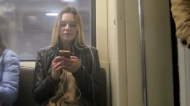 Atractive ile deri ceketli uzun sarı saçlı kız saç kullanım gadget metro düzeltiyor mutlu