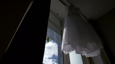 güzel düğün elbisesi bir pencerede asılı.