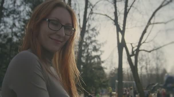 Vacker tjej med rött hår bär glasögon går i park slo-mo — Stockvideo