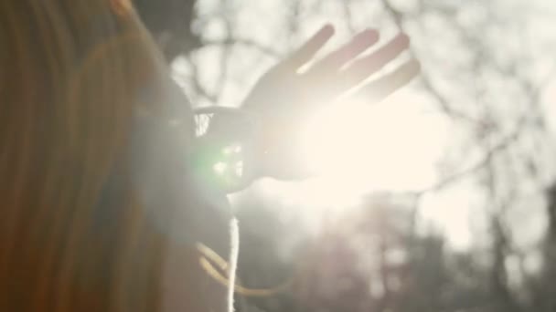 Bella ragazza con i capelli rossi indossando occhiali nel parco primaverile guarda il sole — Video Stock