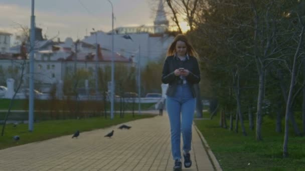 Милая молодая девушка гуляет в парке в сумерках — стоковое видео