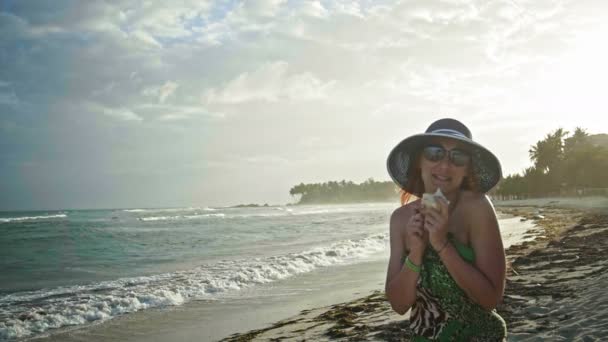 Nahaufnahme Porträt einer schönen jungen Frau mit Sommersprossen, die in einer Muschel singt, Spaß am tropischen Strand in Zeitlupe, Dominikanische Republik — Stockvideo
