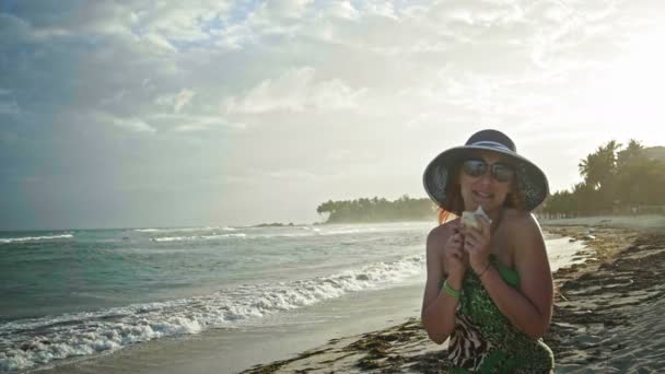 Close-up van portret van mooie jonge vrouw met sproeten zingen in een zee-shell, plezier op tropisch strand Slowmotion, Dominicaanse Republiek — Stockvideo