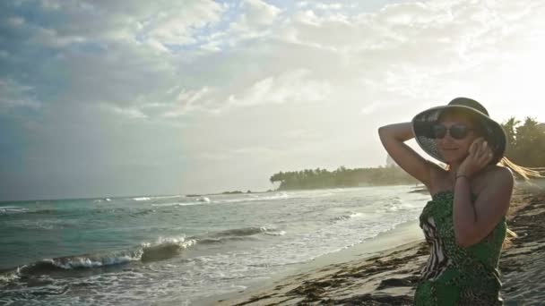 Ritratto ravvicinato di bella giovane donna con lentiggini guardando il guscio sulla spiaggia tropicale, tenere il cappello, rallentatore, Repubblica Dominicana — Video Stock