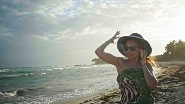 Közelről a gyönyörű fiatal nő portréja a szeplő pózol a seashell trópusi tengerparton, tartsa a kalap, lassú mozgás, Dominikai Köztársaság — Stock videók