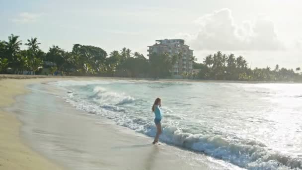 Jeune femme aux longs cheveux roux jouer avec les vagues en cours d'exécution, sentir la mer, paysage marin, grand angle, plage de la République dominicaine — Video