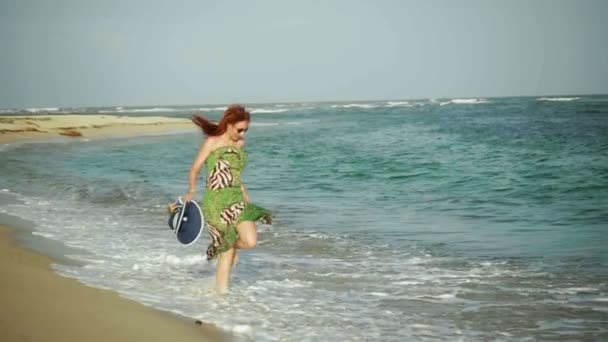 Jeune femme aux longs cheveux roux joue avec les vagues qui courent au coucher du soleil, plage de la République dominicaine — Video