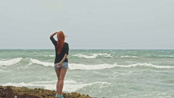 Verleidelijke meisje met lange rode haren draagkracht op het strand in de buurt van de zee van de storm, slow-motion — Stockvideo