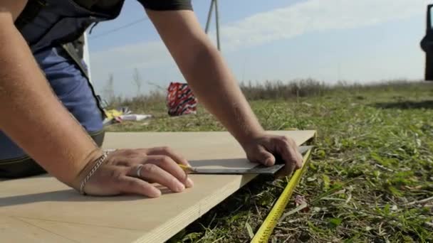 Мужчина измеряет фанеру на стройке — стоковое видео