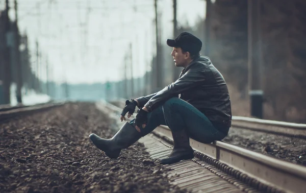 Мужественный человек, сидящий на железной дороге в лесу — стоковое фото