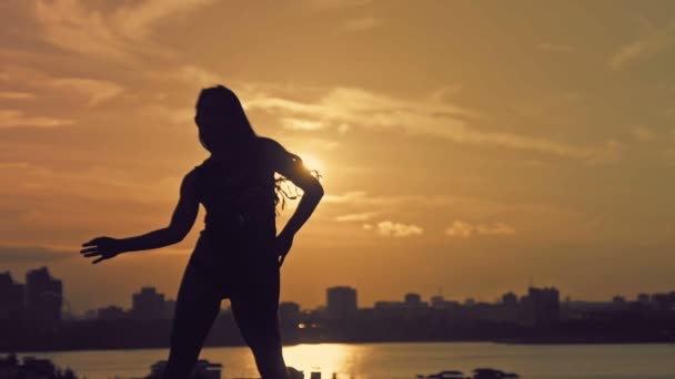 Young attractive girl with flowing hair dancing at sunset silhouette — Stok video