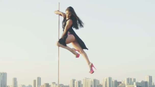 Fit attrayant fille poledancer effectue des tours de pole dance avancés le jour d'été sur scène de danse portable sur la skyline — Video