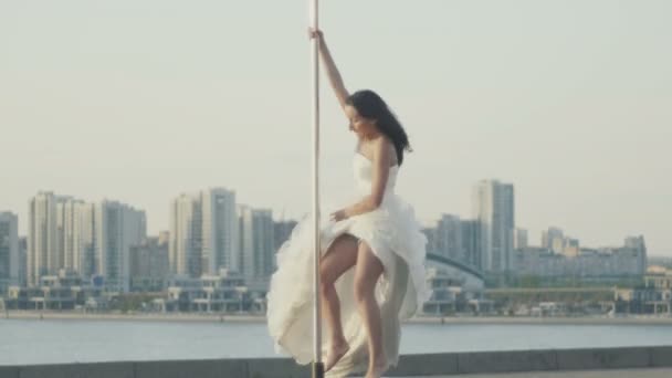 Fit vonzó lány táncol a hordozható pole a nyári napon a menyasszonyi ruha alatt a látóhatár, lassú mozgás, telefotó