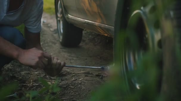 Homem forte levanta carro com Jack na floresta ao entardecer, de perto — Vídeo de Stock