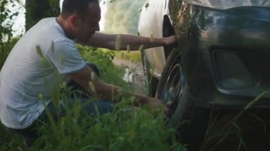 yorgun adam ormanda bir araba tekerleği ayarlar