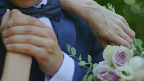 Beautiful bride and groom are kissing in a sunny park, close up — Stock Video