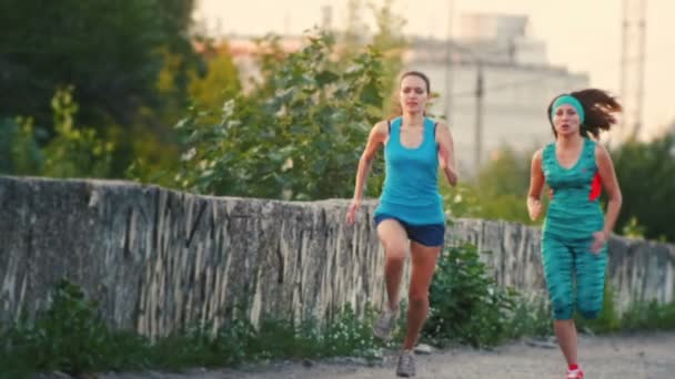 Dos mujeres hermosas corriendo en el parque de la ciudad, cámara lenta — Vídeo de stock