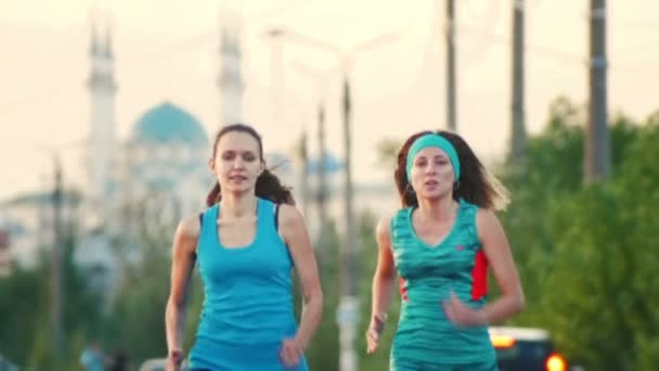 Two young beautiful woman running at city park , the mosque in the background, slow-motion, close-up — Stock Video