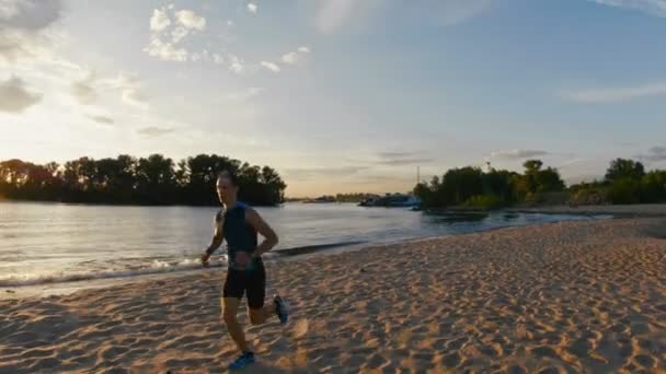 ビーチで強い男性ランナーは彼の息を取り戻すため休憩を取る — ストック動画