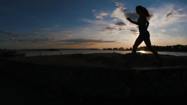 Mujer joven corriendo con el pelo rizado en el parque al atardecer, cámara lenta, silueta — Vídeo de stock