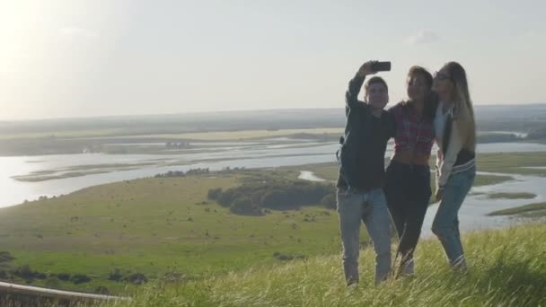 Gruppe junger glücklicher Freunde macht abends Selfies auf einem hohen Sommerberg — Stockvideo