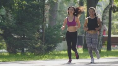 İki çekici Fitness atletik genç kadın kıvırcık saçlı parkta yaz sabahı, yavaş çalışan spor elbise giymiş