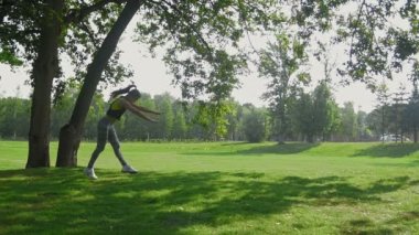 Egzersiz: genç çekici fitness kadın kıvırcık saçlı parkta akrobatik numara yaz sabahı, ağır çekim yapıyor