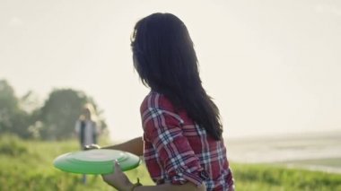 Genç kadın yaz günü güneş doğru yüksek tepe çayırda bir frizbi atma yavaş hareket