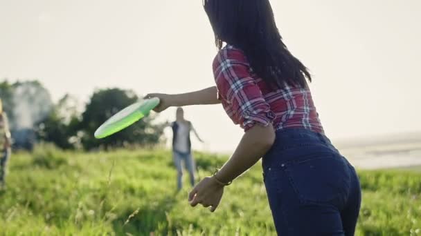 Mujer joven lanzando un frisbee en el día de verano en el prado en la colina alta, cámara lenta — Vídeos de Stock