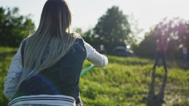 Mujer joven fitness en pantalones vaqueros azules y zapatillas blancas captura de un frisbee en el día de verano en el prado en la colina alta hacia el sol, cámara lenta — Vídeos de Stock