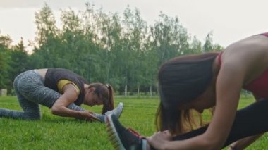 Genç spor kadınlar, esnek - kafa feet - egzersiz yapıyor parkta yakın, dolly vurdu