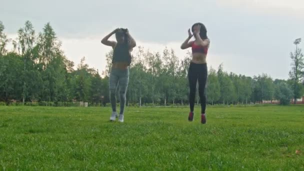 Jóvenes deportistas haciendo ejercicio físico para las piernas en el parque, tiro ancho, dolly shot — Vídeos de Stock