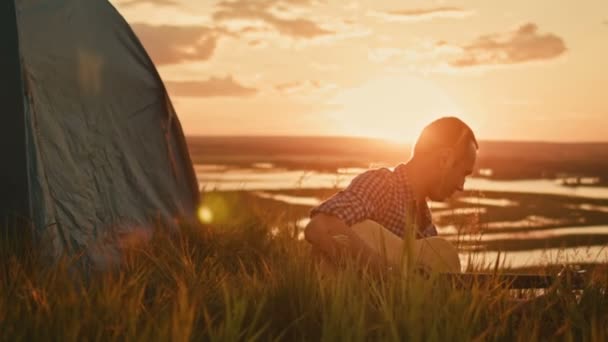 Homme tunes guitare acoustique dans le camping en plein air sur la haute colline au coucher du soleil d'été — Video