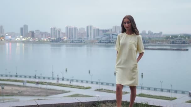 Atraktivní mladé ženy v módní šaty, pózuje pro fotografa nad Panorama za soumraku — Stock video