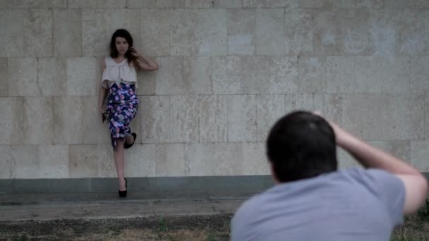 Young attractive woman posing near wall for fashion photographer — Stock Video