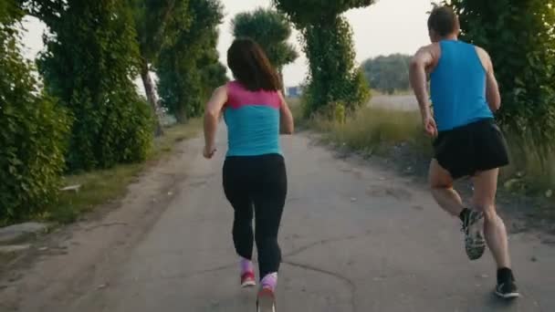 Pareja de adultos jóvenes en el inicio del sprint - corriendo a lo largo del paseo marítimo, cámara lenta, vista trasera — Vídeo de stock