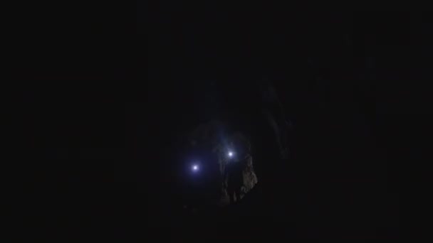 Pareja joven: personas siluetas con linternas entran en la cueva — Vídeos de Stock