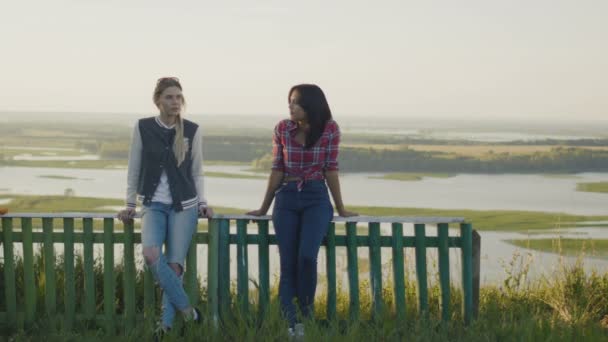 Две привлекательные девушки подруги молодая женщина стоит на высоком холме в летний вечер — стоковое видео