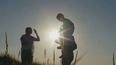 Yaz tatil - baba, anne ve oğul gün batımında mutlu bir aile. Baba oğlunu alır onun kollarında siluet