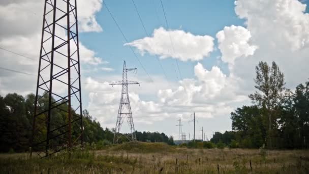 Szeroki strzał timelapse linii energetycznych i słupy wysokiego napięcia na polu na wsi na lato. — Wideo stockowe